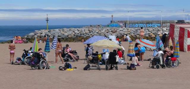 grupo de discapacitados en la playa con sus sillas