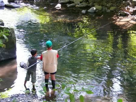 dos niños pescando a caña en un rio